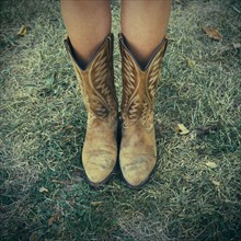 Woman wearing cowboy boots on lawn.