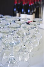 Wine glasses on table with bottles in background.