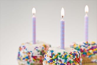 Lit candles on decorated cakes.