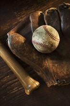 Antique baseball on baseball glove with bat.