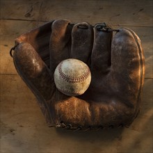 Antique baseball on baseball glove with bat.