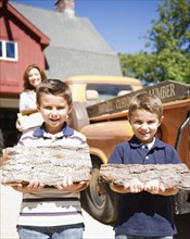 USA, New York, Flanders, Two boys (4-5, 8-9) holding firewood. Photo : Jamie Grill Photography