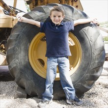 USA, New York, Flanders, Boy (4-5) standing in front of tractor wheel. Photo : Jamie Grill
