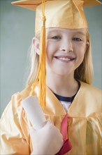 USA, New Jersey, Jersey City, Girl (8-9) wearing yellow mortar board and graduation gown. Photo :