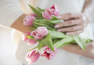 USA, New Jersey, Jersey City, Woman's hands holding bunch of pink tulips. Photo : Jamie Grill