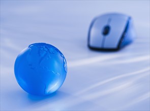 Close-up view of blue computer mouse and globe. Photo : Daniel Grill