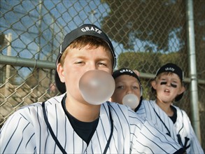 USA, California, Ladera Ranch, Boys (10-11) from little league sitting on dugout and blowing bubble