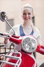 USA, Seattle, Young smiling woman on scooter, portrait. Photo : Take A Pix Media