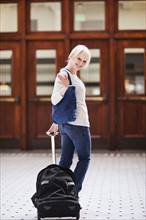 USA, Seattle, Young woman at train station standing with luggage and looking at camera. Photo :