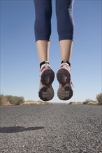 USA, Arizona, Winslow, Mid adult woman jumping, low section. Photo : David Engelhardt