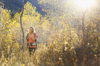 USA, Utah, young woman hiking in forest and talking on mobile phone. Photo : Mike Kemp