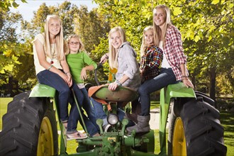 USA, Utah, family portrait of sisters (6-7, 8-9, 12-13, 14-15, 16-17) sitting on tractor. Photo :