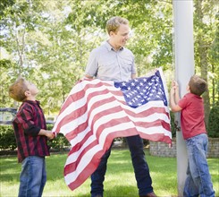 USA, New York, Flanders, Father with two boys (4-5, 8-9) hanging American flag on pole. Photo :