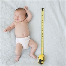 USA, New Jersey, Jersey City, baby girl laying (2-5 months) laying next to measuring tape. Photo :