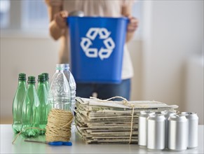 Woman recycling plastic bottles, cans and newspapers.