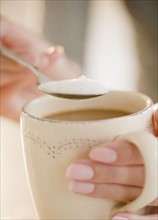 USA, New Jersey, Jersey City, Close-up view of human hand putting sugar into cup of coffee. Photo :