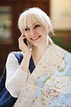 USA, Seattle, Young woman talking via phone and holding map. Photo : Take A Pix Media