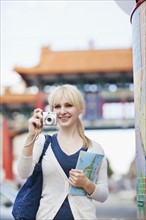 USA, Seattle, Young woman taking photos and holding map. Photo : Take A Pix Media