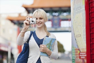 USA, Seattle, Young woman taking photos and holding map. Photo : Take A Pix Media