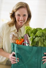 USA, New Jersey, Jersey City, Portrait of woman holding grocery bag in kitchen.