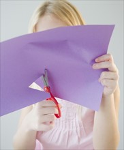 USA, New Jersey, Jersey City, Girl (8-9) cutting star shape in paper. Photo : Jamie Grill