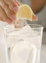 USA, New Jersey, Jersey City, Close-up view of woman's hand squeezing lemon into refreshness drink.
