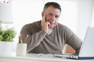 USA, New Jersey, Jersey City, Portrait of man using laptop in living room.