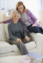 USA, New Jersey, Jersey City, Portrait of mother and daughter smiling on sofa.