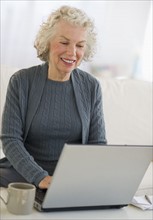 USA, New Jersey, Jersey City, Senior woman using laptop at home.