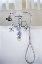 Shower head connected to tap on bath.