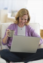 USA, New Jersey, Jersey City, Woman using laptop in living room.