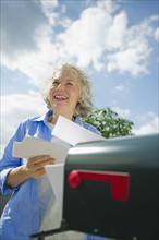 USA, New Jersey, Jersey City, Senior woman checking mail at mailbox.