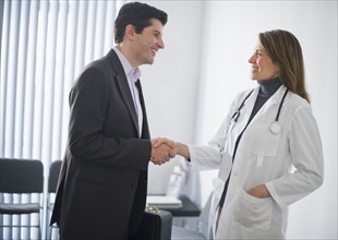 USA, New Jersey, Jersey City, Medical sales representative shaking hands with female doctor in office.