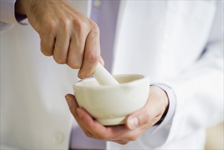 USA, New Jersey, Jersey City, Doctor preparing medicine using mortar and pestle.