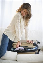 USA, New Jersey, Jersey City, Woman packing suitcase on sofa.