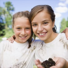 USA, New York, Two girls (10-11, 10-11) holding soil wearing dirty t-shirts. Photo : Jamie Grill