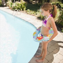 USA, New York, Girl (10-11) standing next to swimming pool. Photo : Jamie Grill Photography