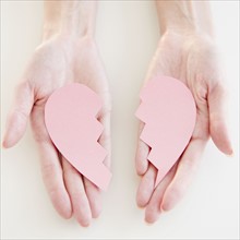 USA, New Jersey, Jersey City, Woman's hand holding two halves of heart. Photo : Jamie Grill