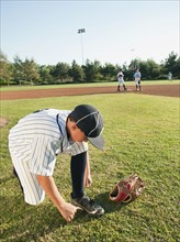 USA, California, boy (10-11) from little league baseball team tying lace.