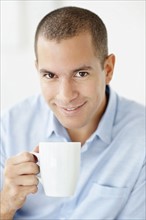 South Africa, Portrait of smiling man holding mug. Photo : momentimages