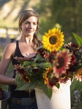 USA, Colorado, Young woman carrying bucket with sunflowers. Photo : John Kelly