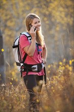 USA, Utah, young woman hiking in forest and talking on mobile phone. Photo : Mike Kemp