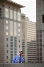USA, Utah, Salt Lake City, Young businessman talking on mobile phone in front of skyscrapers. Photo