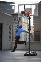 USA, Utah, Salt Lake City, Young businessman scoring basketball goal. Photo : Mike Kemp