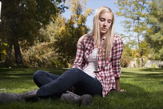 USA, Utah, outdoor portrait of blonde teenage girl (14-15) sitting on grass. Photo : Tim Pannell