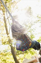 USA, Utah, rear view of girl (6-7) hanging on rope. Photo : Tim Pannell