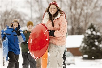 USA, Utah, Provo, Teenage (16-17) girl running with sledge, boys and girls (10-11, 12-13) in