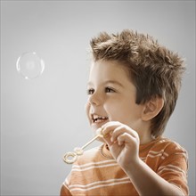 Studio portrait of boy (8-9) blowing bubbles. Photo : FBP