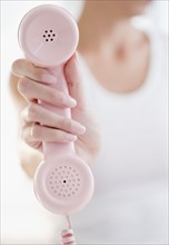 USA, New Jersey, Jersey City, Woman's hand holding pink telephone receiver. Photo : Jamie Grill