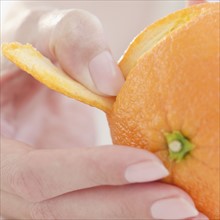 USA, New Jersey, Jersey City, Close-up view of woman's hand peeling orange. Photo : Jamie Grill